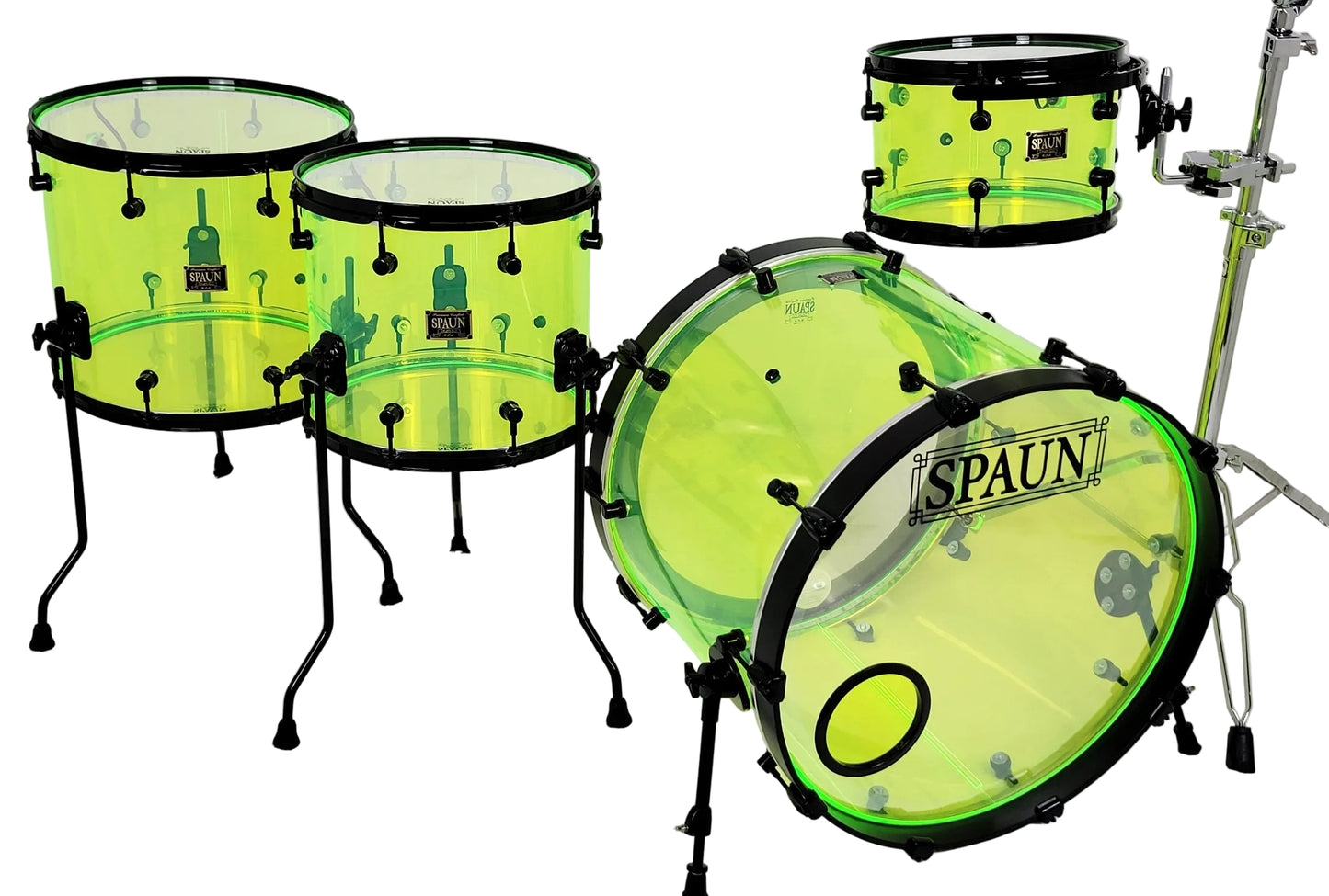 A complete drum kit with transparent neon yellow-green shells and black hardware, including a bass drum, two tom drums on stands, a mounted tom, and a cymbal stand, on a white studio background. The bass drum features the 'SPAUN' brand logo.