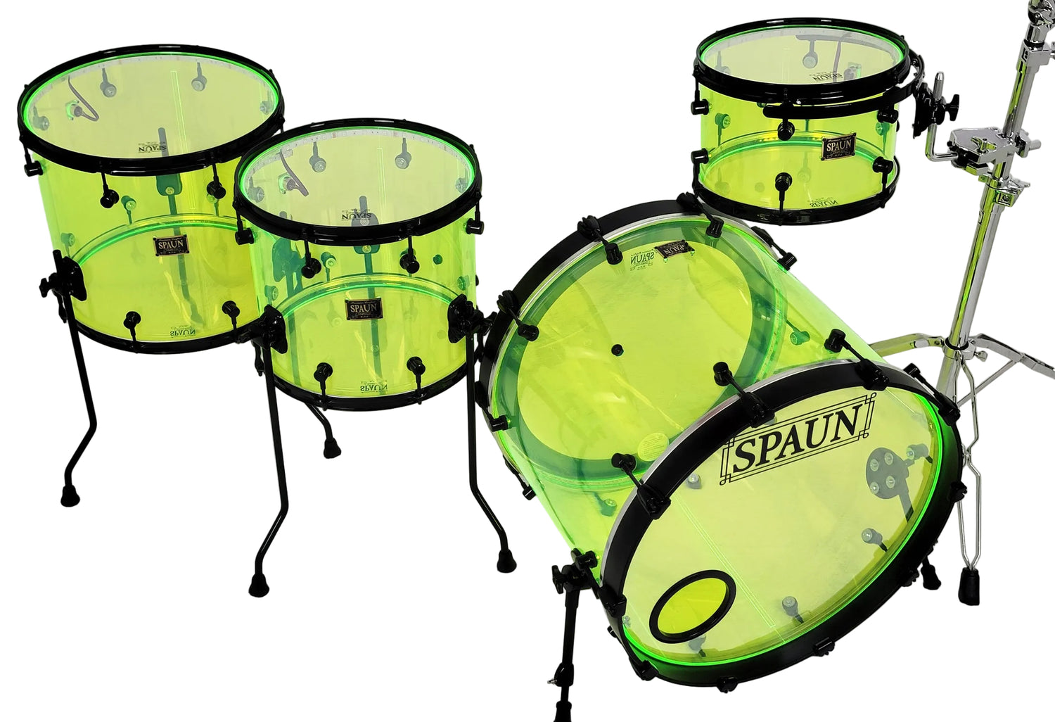 A drum set with translucent neon yellow-green shells and black rims, including a bass drum, two tom drums, a floor tom, and a cymbal stand, photographed against a plain white studio background. The front of the bass drum shows the visible brand name SPAUN.